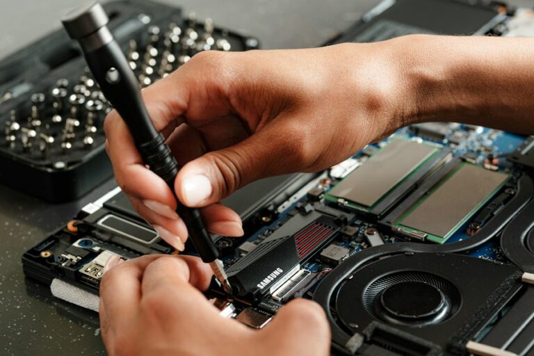Handen openen een elektronisch apparaat met een precisieschroevendraaier